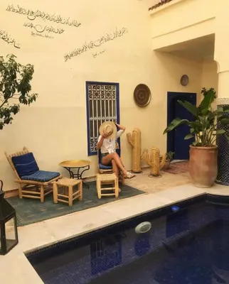 a person sitting in a chair next to a pool at Riad Hotel Sherazade in Marrakech