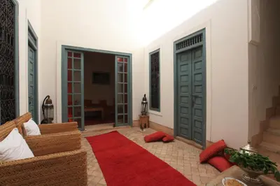 a living room with green doors and a red rug at Riad Dar Aicha en Exclusivité in Marrakech