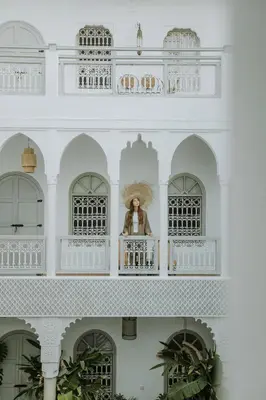 a woman standing on a balcony of a white building at Riad Oriental Glory & Spa in Marrakech