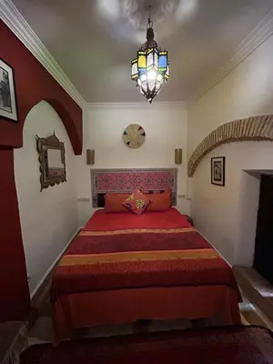 a bedroom with a large bed with a chandelier at Riad N10 in Marrakech