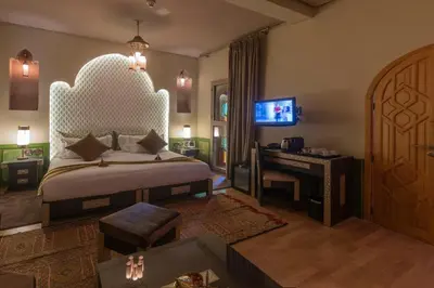 a bedroom with a bed and a desk and a television at Palais Dar Si Aissa ALL-SUITES in Marrakech