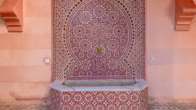 a fountain in front of a wall with a red door at L'OLIVERAIE DE L'ATLAS in Marrakech