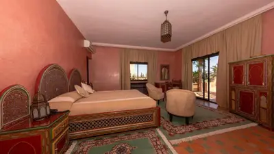 a bedroom with a bed and a table and chairs at L'OLIVERAIE DE L'ATLAS in Marrakech