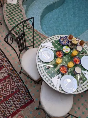 a table with a plate of food on it next to a pool at Riad Smara in Marrakech