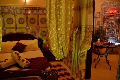 a bedroom with a bed and a curtain and a table at Dar LEULEU in Marrakech