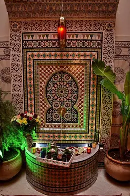 a room with a fountain with plants in front of a wall at Dar LEULEU in Marrakech