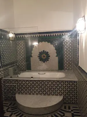 a bathroom with a tub and a tile wall at Riad Dar El Assafir in Marrakech