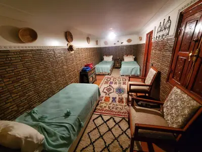 a room with two beds and a chair in it at Riad Lalla Marrakech in Marrakech