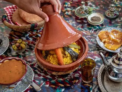 a person holding a pot of food on a table at Riad Lalla Marrakech in Marrakech