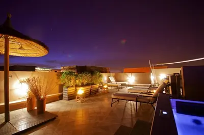 a rooftop patio with couches and an umbrella at night at Riad Kasbah 117 in Marrakech