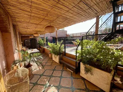 a patio with potted plants and a balcony at Riad Ecila in Marrakech
