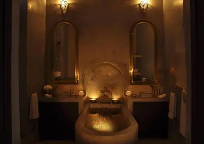 a bathroom with two sinks and a tub with two mirrors at Riad Dar Jaguar in Marrakech