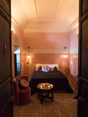 a bedroom with a bed and a table and a chair at Riad Dar Jaguar in Marrakech