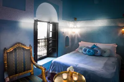a bedroom with a bed with blue walls and a window at Riad Dar Jaguar in Marrakech