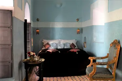 a bedroom with a bed and a chair and a table at Riad Dar Jaguar in Marrakech