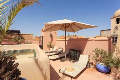 a patio with an umbrella and chairs and a pool at Riad Julia in Marrakech