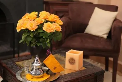 a vase of yellow roses and a candle on a table at Riad Monceau in Marrakech