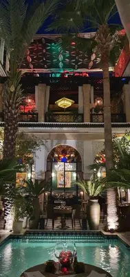 a hotel lobby with a swimming pool and palm trees at Riad Monceau in Marrakech