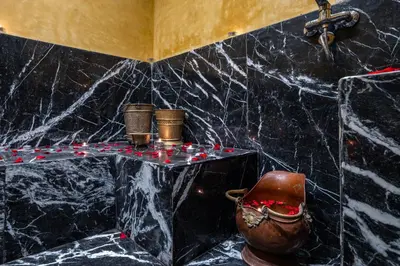 a bathroom with a black marble wall with a table and a pitcher at Dar Khmissa Riad & Spa in Marrakech