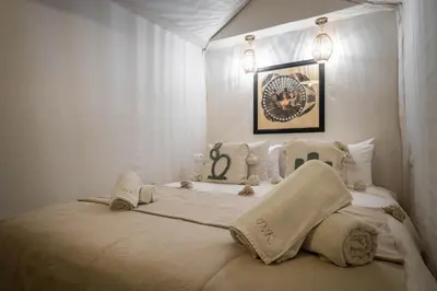 a white bedroom with a bed with towels on it at Dar Khmissa Riad & Spa in Marrakech