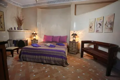 a bedroom with a bed with pink pillows and a chair at Riad Turquoise in Marrakech