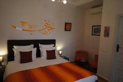 a bedroom with a bed with a orange and orange blanket at Riad Shanima SPA Marrakech in Marrakech