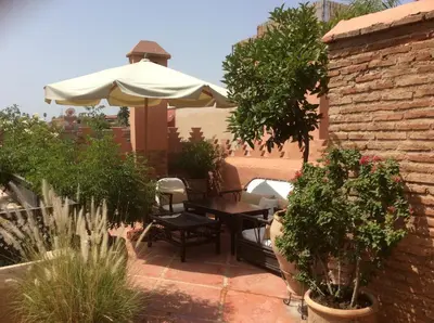 a patio with a table and an umbrella at Dar Attajmil in Marrakech
