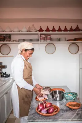 a woman standing in a kitchen preparing food at Dar Attajmil in Marrakech