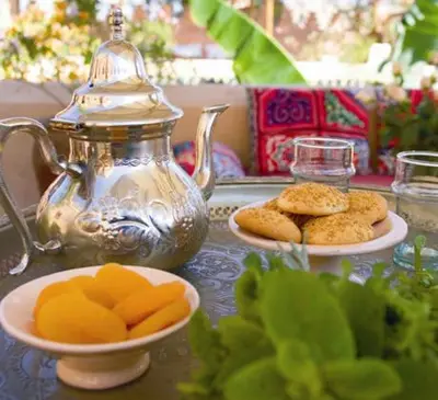a table with a tea kettle and plates of food at Dar Attajmil in Marrakech