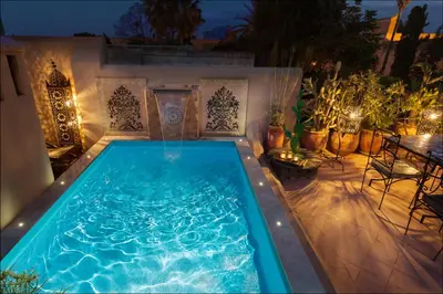 a swimming pool in a backyard at night at Riad Swaka in Marrakech