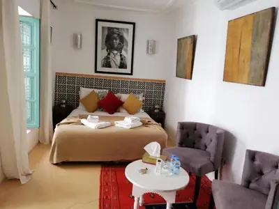 a bedroom with a bed and a table and chairs at Riad Swaka in Marrakech