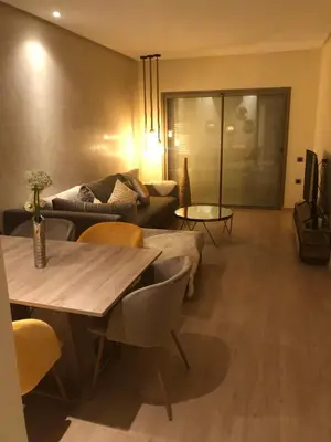 a living room with a table and a couch at Appartement à Prestigia Marrakeche avec jardin in Marrakech