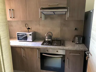 a small kitchen with a microwave and a stove at Appartement à Prestigia Marrakeche avec jardin in Marrakech