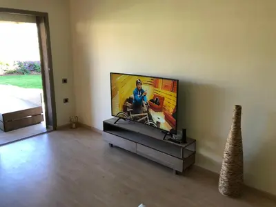 a living room with a flat screen tv on a wall at Appartement à Prestigia Marrakeche avec jardin in Marrakech