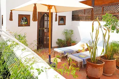 a patio with an umbrella and benches and plants at Riad la Parenthèse by Sashema in Marrakech