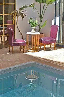 two chairs and a table next to a pool at Riad la Parenthèse by Sashema in Marrakech