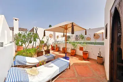 a patio with a bunch of chairs and an umbrella at Riad la Parenthèse by Sashema in Marrakech