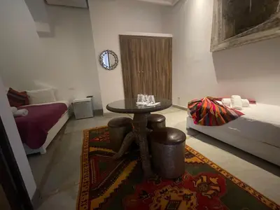 a living room with a table and a bed at Riad Samarine in Marrakech