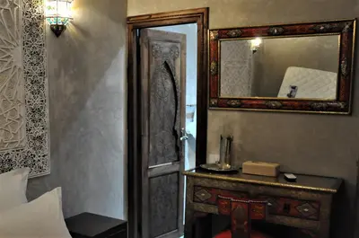 a bedroom with a door and a mirror and a table at Riad Sania By Ghali in Marrakech