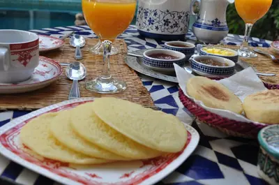 a table topped with plates of bread and glasses of orange juice at Riad Sania By Ghali in Marrakech
