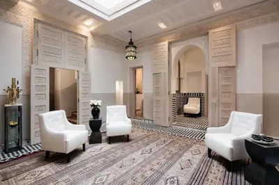 a living room with white chairs and a fireplace at Le Farnatchi in Marrakech