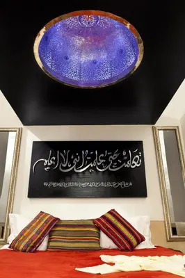 a large purple plate hanging over a bed with a bedspread at Le Farnatchi in Marrakech