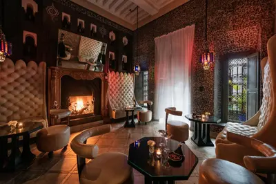 a room with a fireplace and chairs and a table at Le Farnatchi in Marrakech