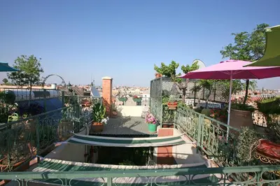 a balcony with a table and an umbrella at Riad Cherihane in Marrakech
