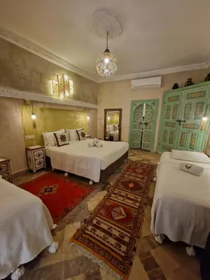 a bedroom with two beds and a rug at Riad Dalla Santa in Marrakech