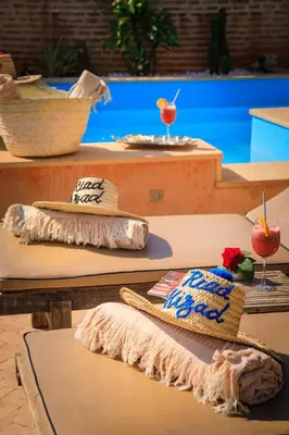 a table with a hat and two glasses on it at Riad Hizad in Marrakech