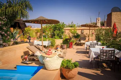 a patio with tables and chairs and an umbrella at Riad Hizad in Marrakech