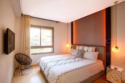a bedroom with a large bed and a window at Darkech Prestigia Luxury Apt in Marrakech
