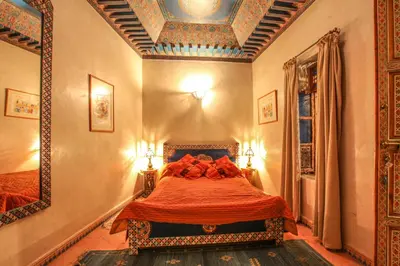 a bedroom with a bed with red sheets and a mirror at Riad Puchka in Marrakech
