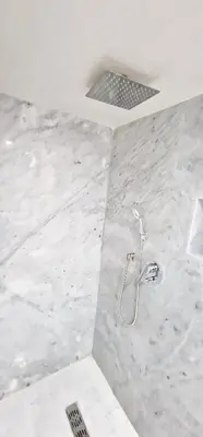 a shower in a bathroom with white marble tiles at Riad de Vincent in Marrakech